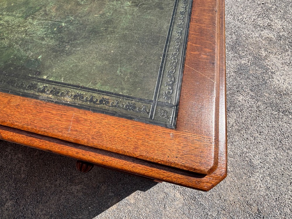 A 19th-century oak partners desk featuring a green leather inset top, two pedestals with multiple drawers, and carved wooden handles. View IX