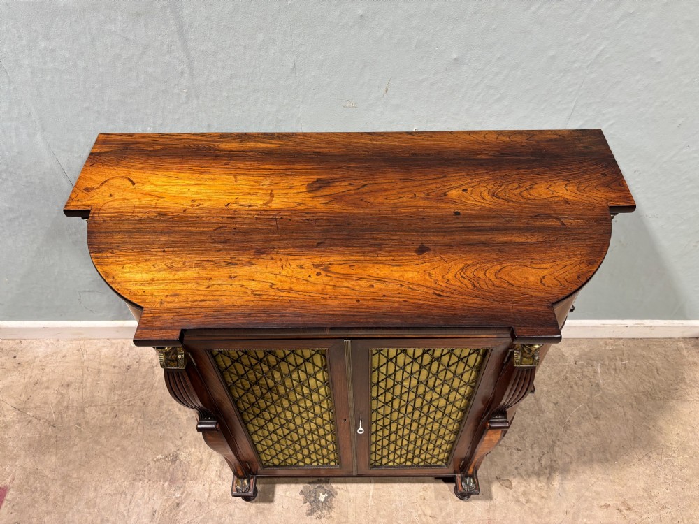 An early 19th-century Regency Egyptian Revival rosewood side cabinet with bow front, brass trellis doors, and a matching overmantel wall mirror. View XII