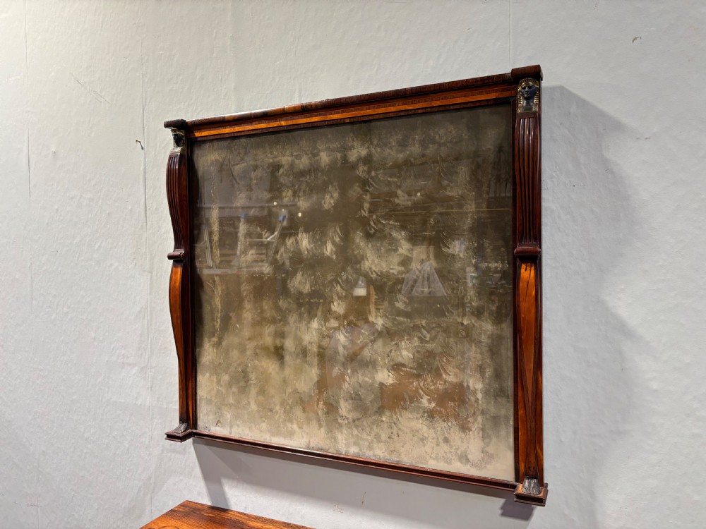 An early 19th-century Regency Egyptian Revival rosewood side cabinet with bow front, brass trellis doors, and a matching overmantel wall mirror. View XVIII