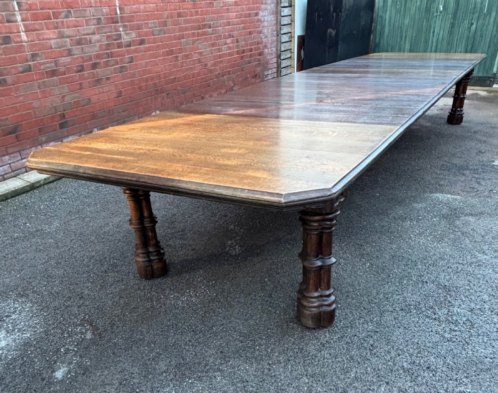 An 18-foot long 19th-century Gothic Revival solid oak table featuring carved clustered column legs and a plank top.