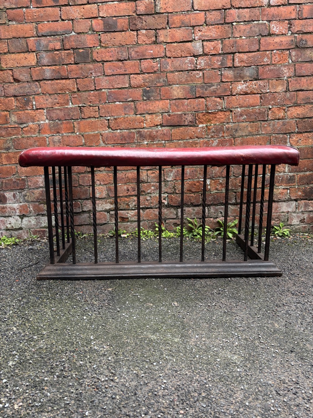 An antique 19th-century steel club fender featuring a red leather padded top seat supported by vertical steel spindles on a moulded metal base. View II