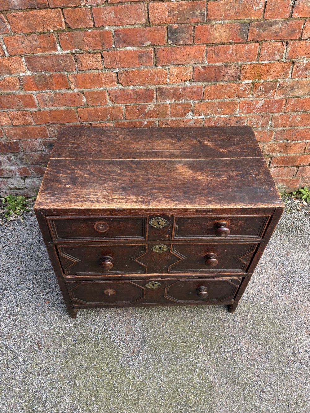 A dark oak 17th-century chest of drawers featuring geometric moulded drawer fronts, turned wooden handles, and brass escutcheons. View III