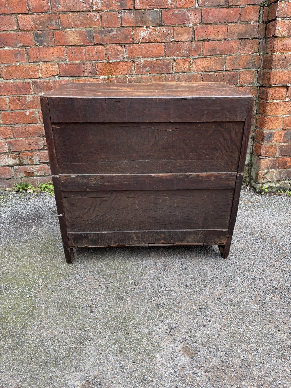 A dark oak 17th-century chest of drawers featuring geometric moulded drawer fronts, turned wooden handles, and brass escutcheons. View VI