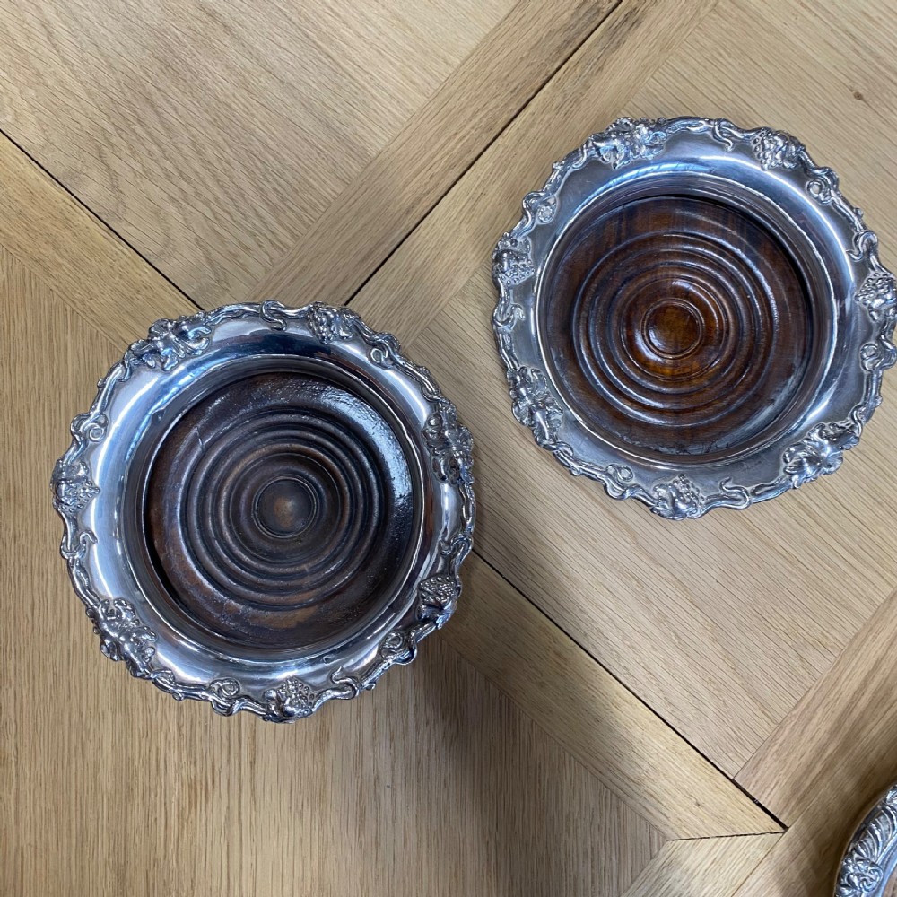 A pair of late nineteenth-century silver-plated wine coasters featuring relief grapevine borders and turned dark wood bases. View II