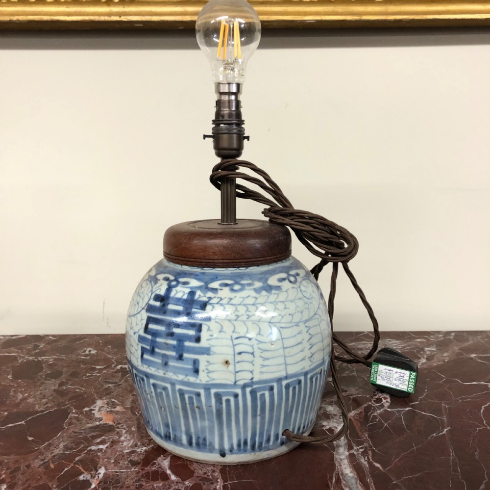 An early 19th-century blue and white Chinese porcelain ginger jar decorated with hand-painted character motifs and fitted as a table lamp with a dark wooden lid.