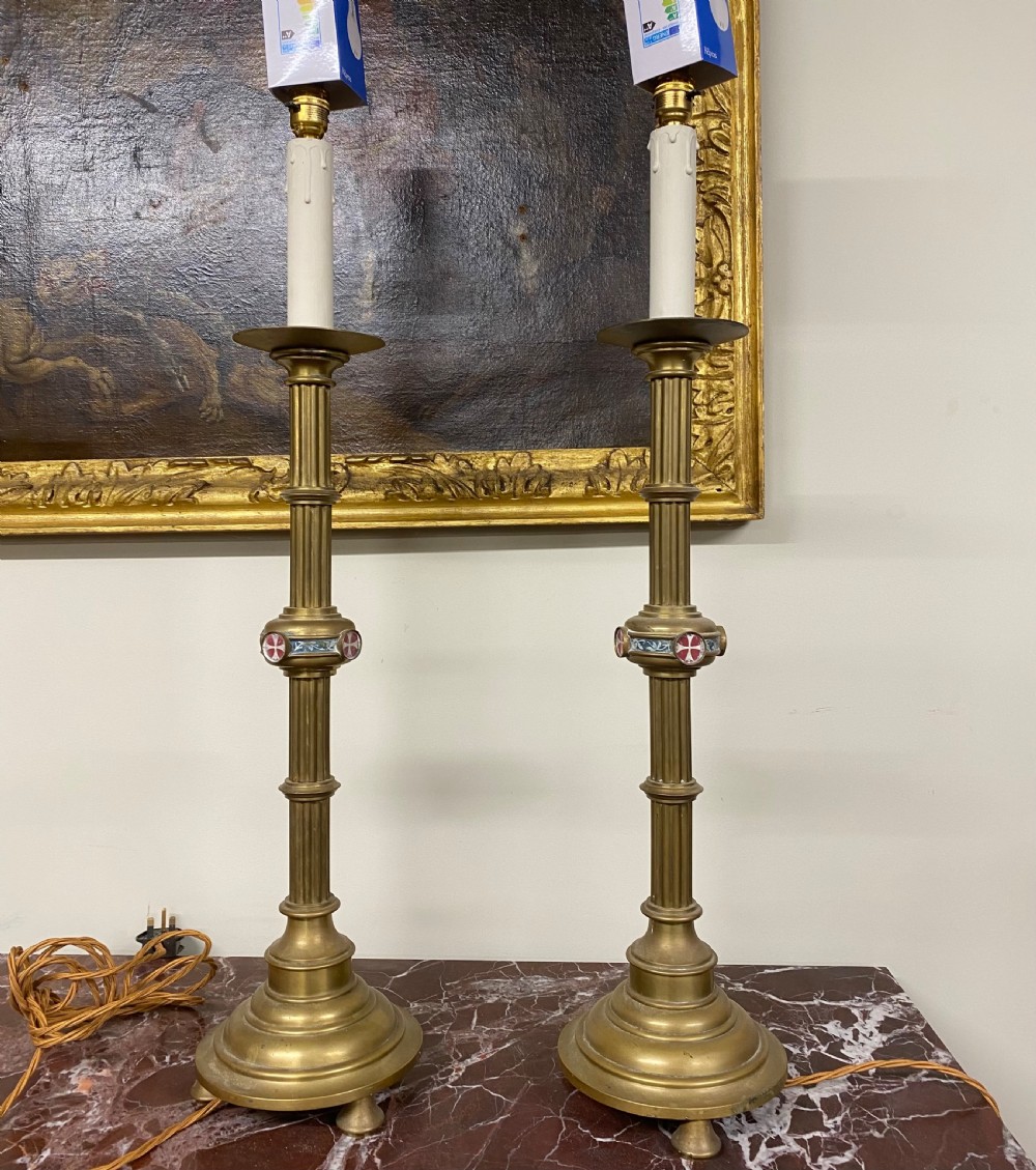 A pair of 19th-century Gothic Revival brass candlesticks converted into electric table lamps featuring fluted columns and red enamel knop details.