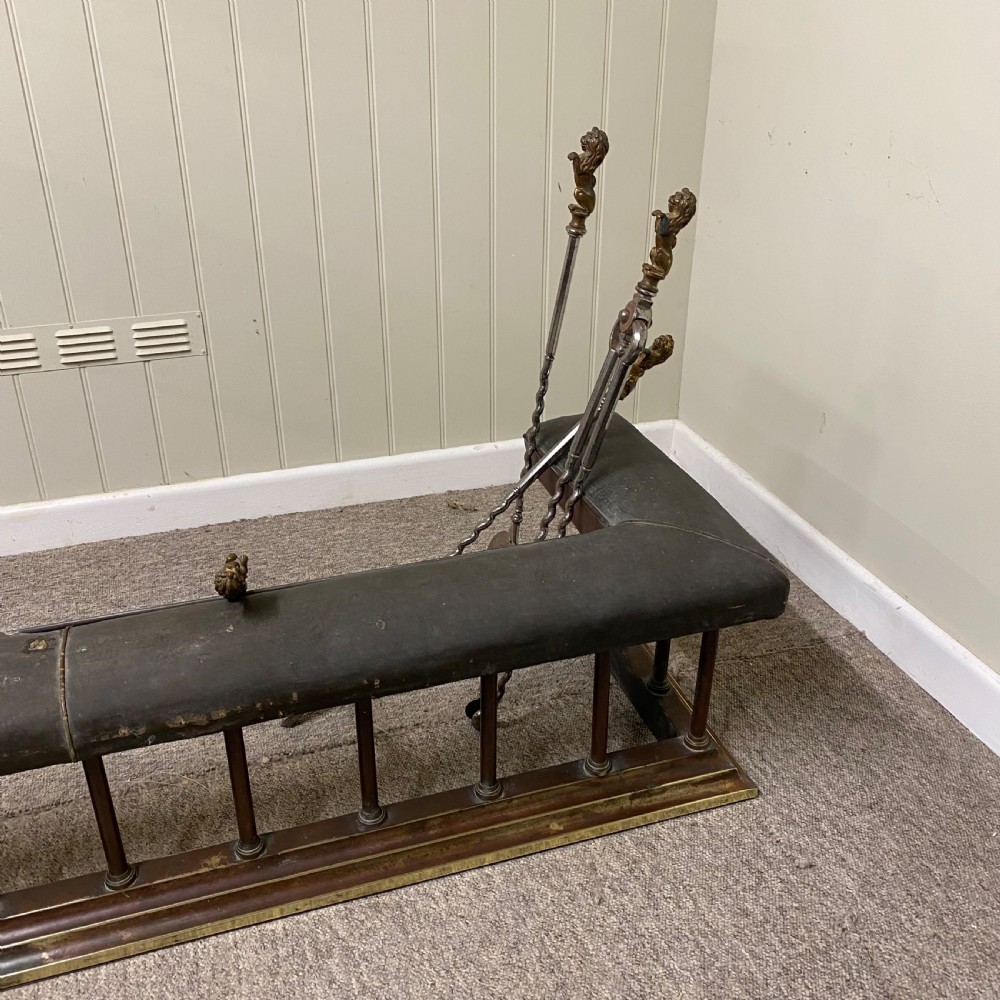 A Victorian club fender featuring a dark brown leather upholstered seat rail supported by turned wooden spindles on a polished wood and brass base. View IV