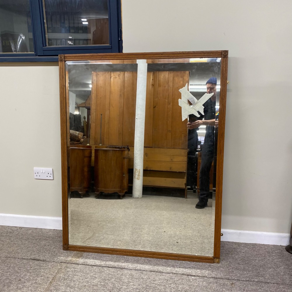 A large rectangular Edwardian oak overmantel mirror featuring reeded frame moulding and square corner rosettes.
