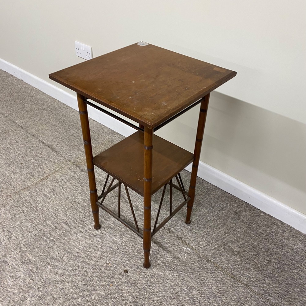 An Aesthetic Movement style dark brown wooden side table featuring slender ring-turned legs, a square top surface, a lower shelf, and angled spindle stretchers. View III