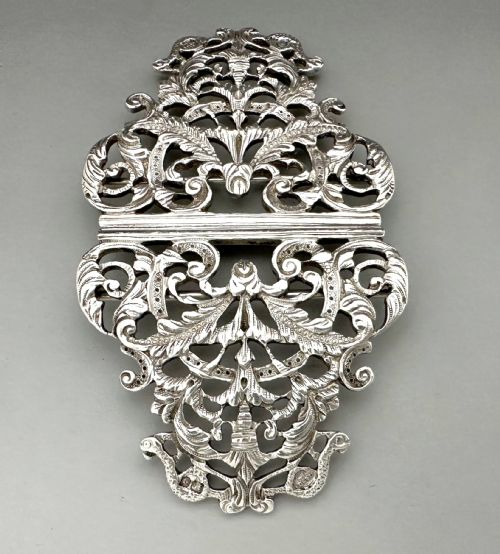 fig 1. An ornate two-part cast silver buckle featuring intricate pierced foliate scrollwork and a central vertical connecting slot.