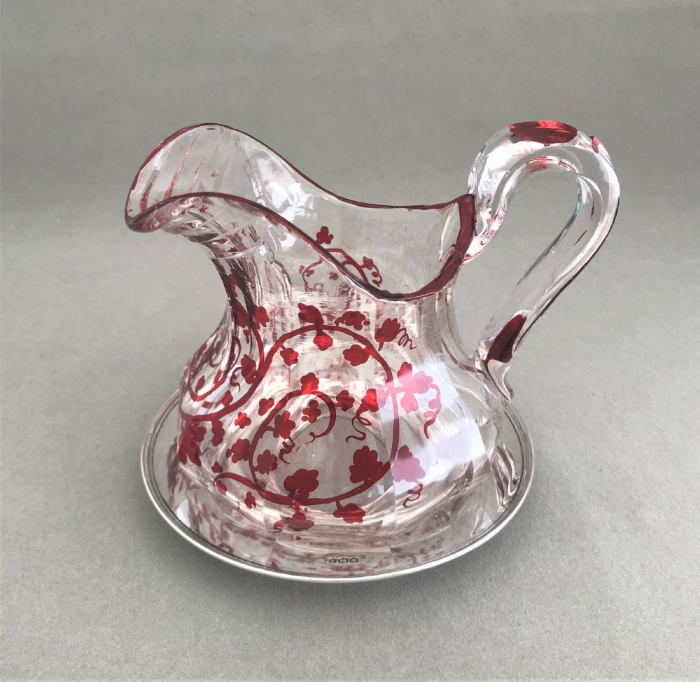 A gorgeous cut glass cream jug with silver drip saucer