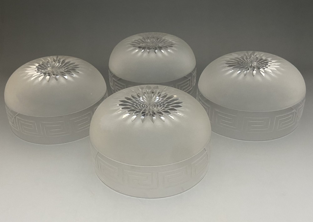 A matching set of four clear glass Victorian finger bowls featuring an etched Greek Key border pattern and a starburst cut base. View IV