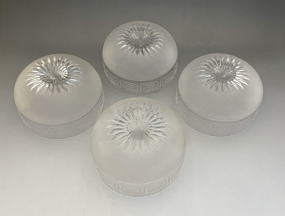 A matching set of four clear glass Victorian finger bowls featuring an etched Greek Key border pattern and a starburst cut base. View V