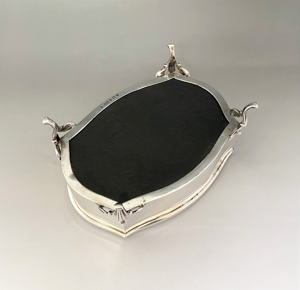 An octagonal silver trinket box with four cabriole legs, an engraved monogram on the top, and stamped hallmarks on the side. View VIII