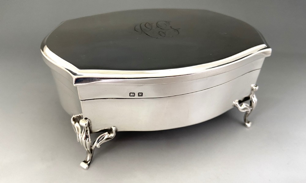 An octagonal silver trinket box with four cabriole legs, an engraved monogram on the top, and stamped hallmarks on the side. View IX