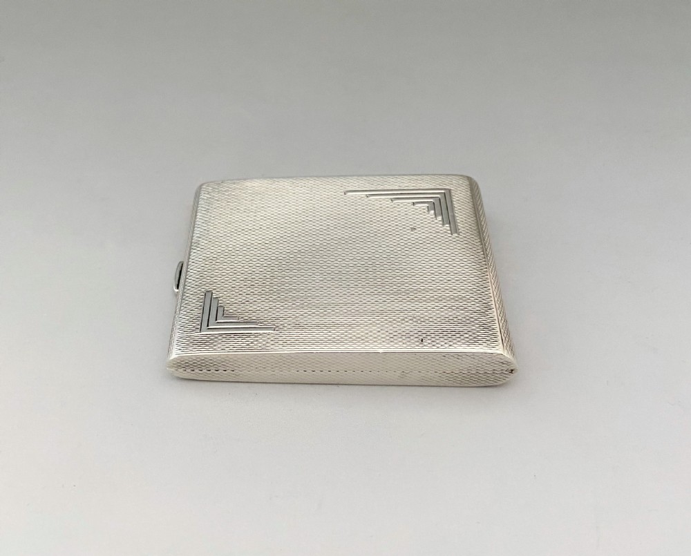 An Art Deco rectangular silver matchbook case featuring engine-turned crosshatch texturing and geometric stepped motifs in opposite corners. View II