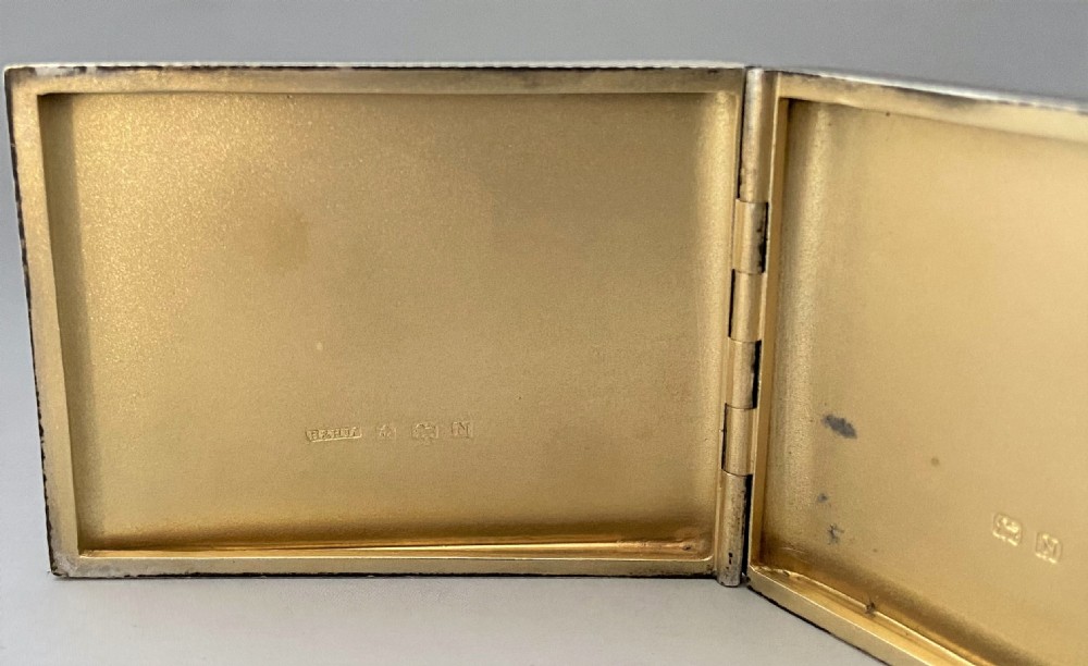 An Art Deco rectangular silver matchbook case featuring engine-turned crosshatch texturing and geometric stepped motifs in opposite corners. View VI