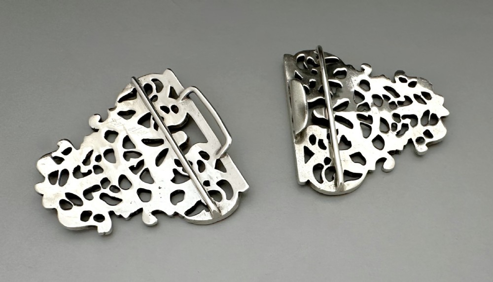 An ornate two-part cast silver buckle featuring intricate pierced foliate scrollwork and a central vertical connecting slot. View V