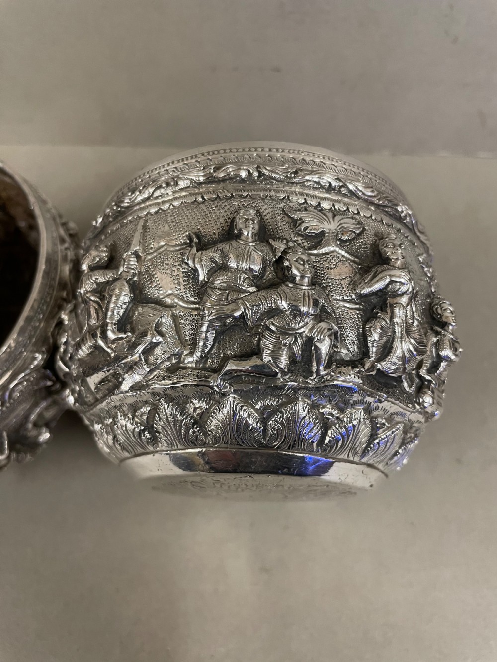 A pair of round antique Burmese silver bowls featuring dense, high-relief figural scenes and traditional chased ornamentation. View III