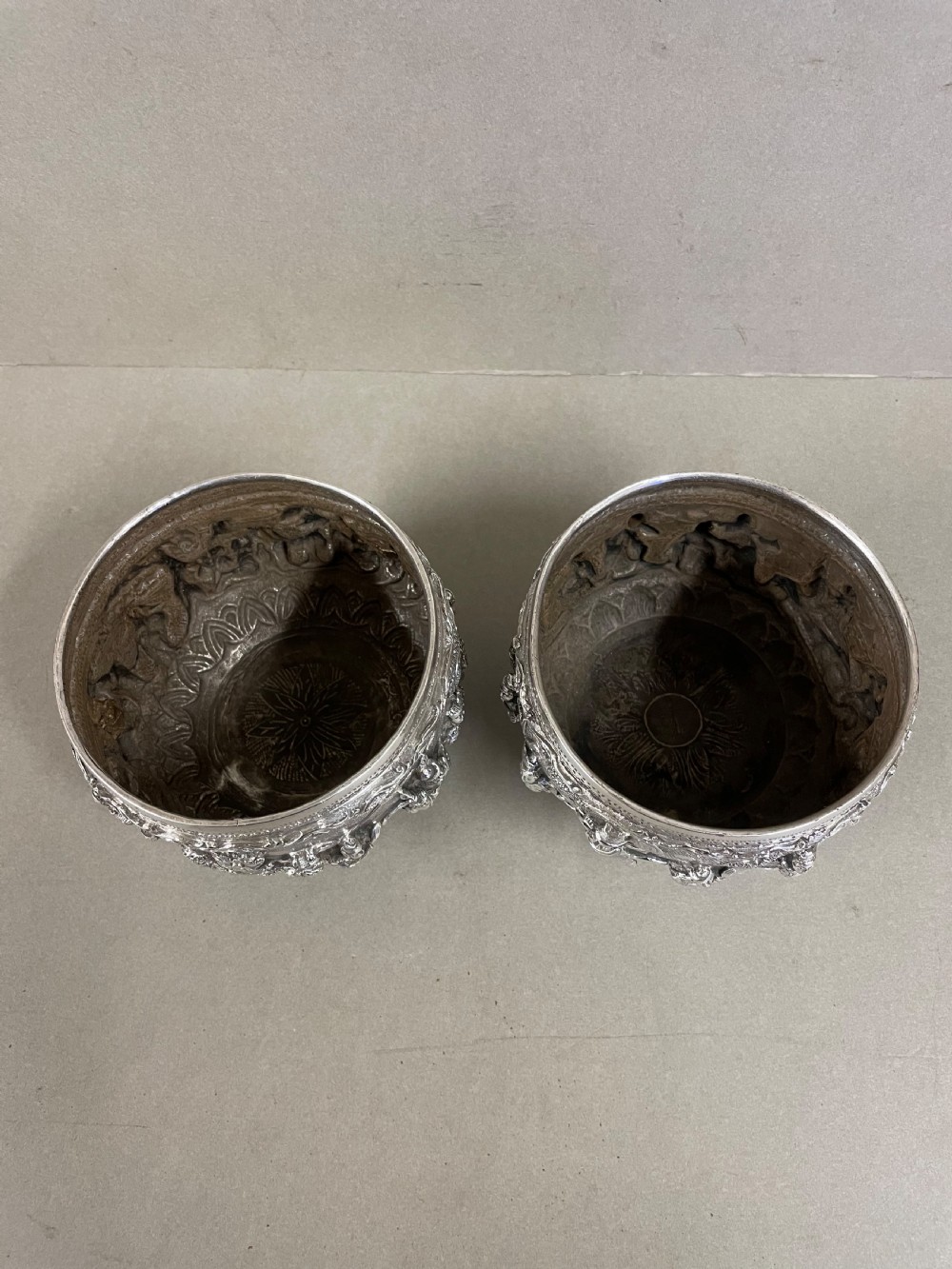 A pair of round antique Burmese silver bowls featuring dense, high-relief figural scenes and traditional chased ornamentation. View VI