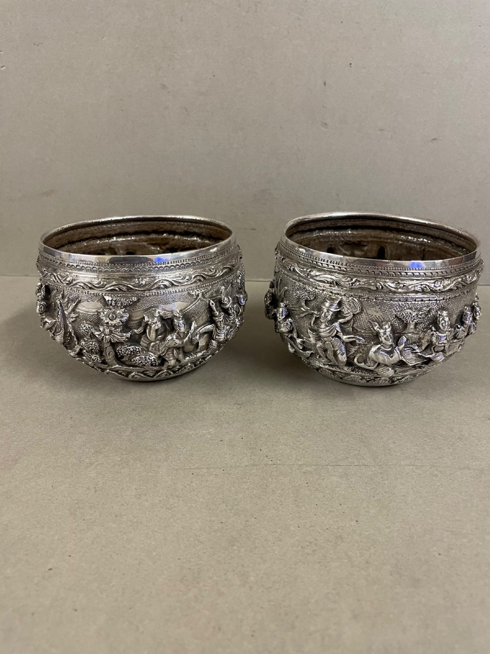 A pair of round antique Burmese silver bowls featuring dense, high-relief figural scenes and traditional chased ornamentation. View VII
