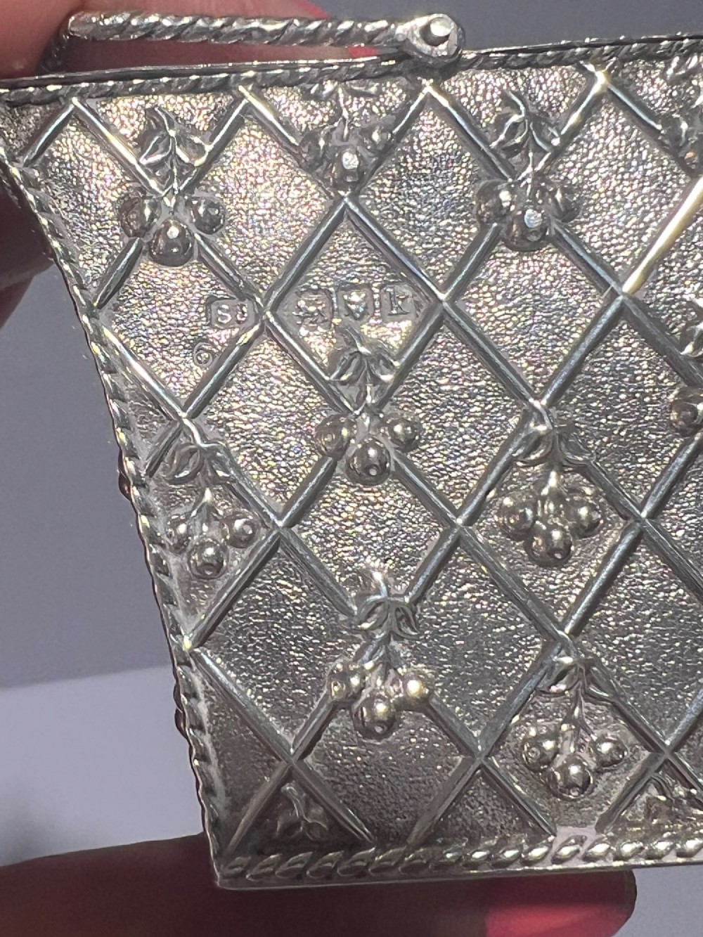 A small silver basket featuring double hinged pierced lids, a central rope-twist handle, and a diaper-patterned body with floral motifs. View IV