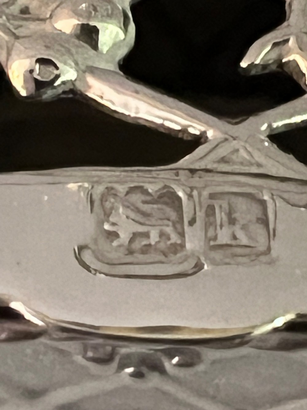 A small silver basket featuring double hinged pierced lids, a central rope-twist handle, and a diaper-patterned body with floral motifs. View V