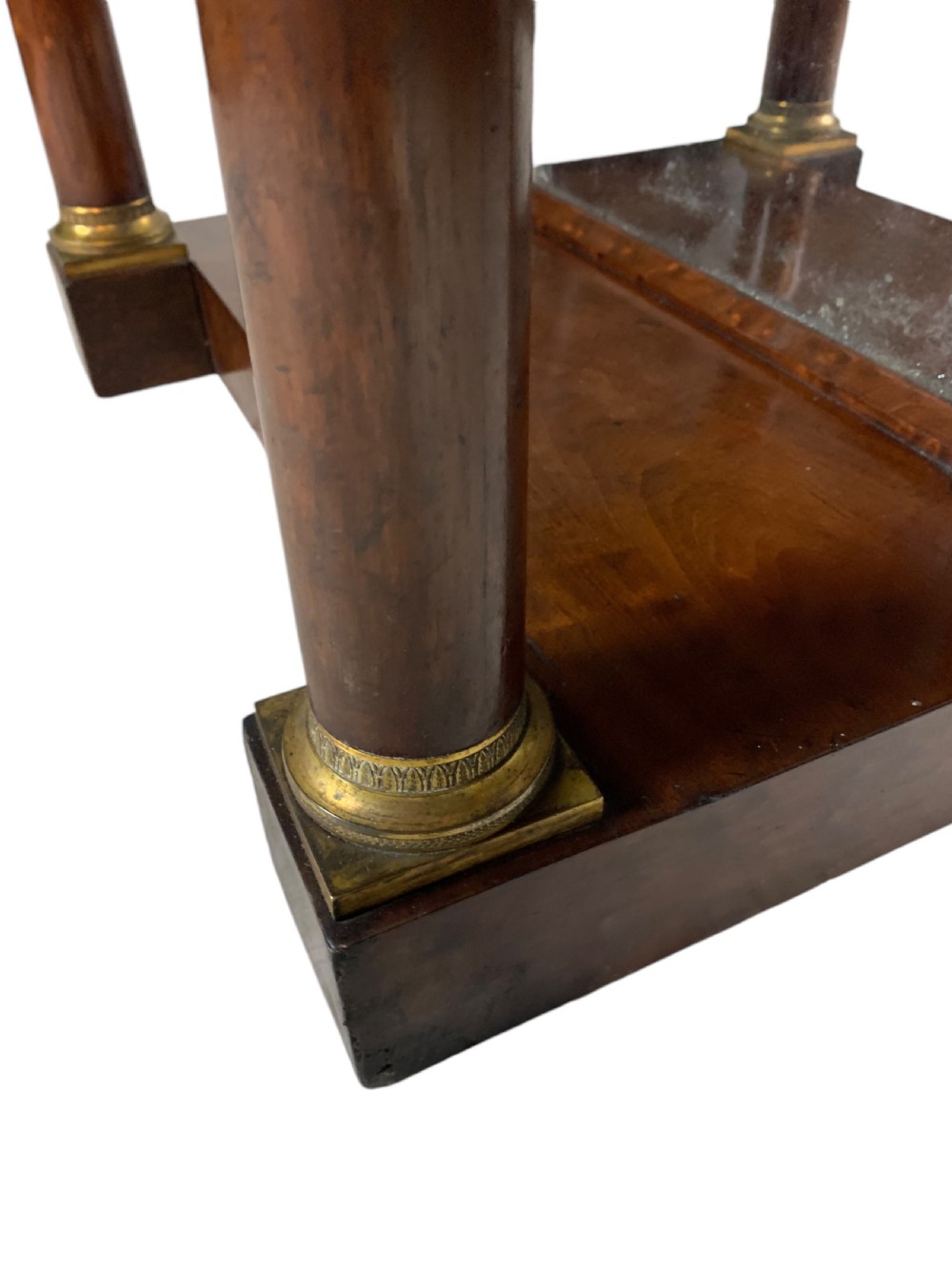 A French Empire mahogany console table featuring a grey marble top, gilt bronze column capitals, a central figural frieze mount, and a mirrored back plate. View IV