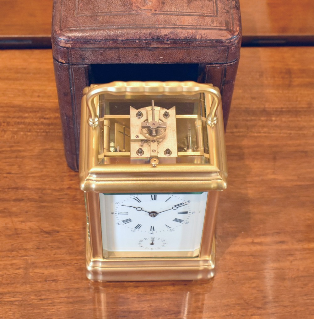 A French gilt brass carriage clock featuring a rectangular glass case, top carrying handle, and white enamel dial with Roman numerals. View III