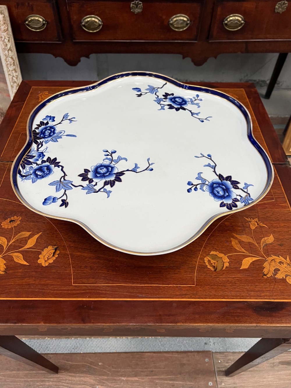 A Royal Worcester porcelain lazy susan featuring a scalloped rim with a cobalt blue and gilt border, decorated with blue floral chinoiserie motifs on a white ground.