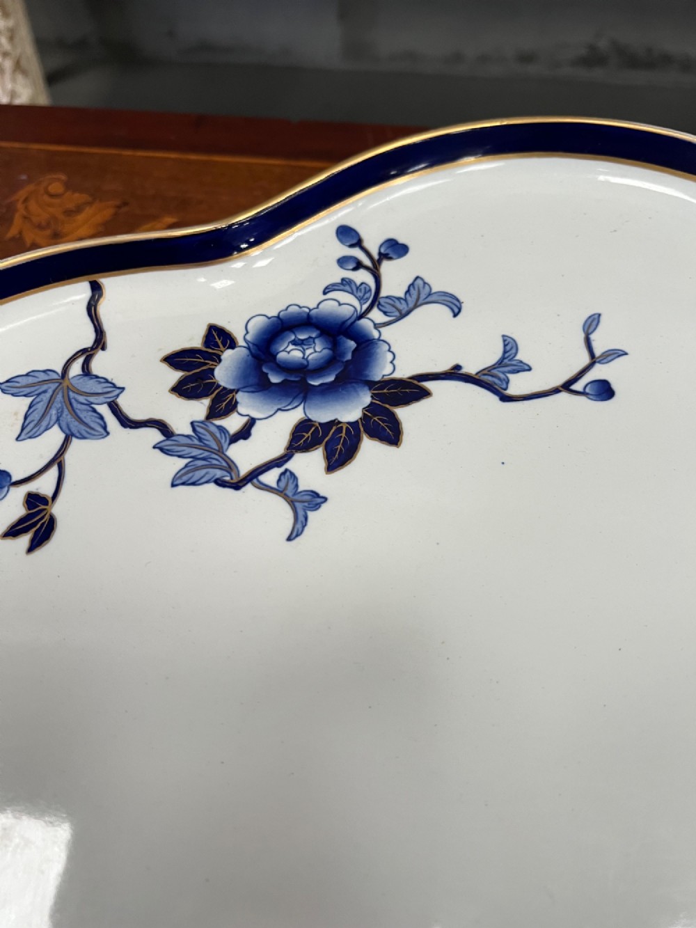 A Royal Worcester porcelain lazy susan featuring a scalloped rim with a cobalt blue and gilt border, decorated with blue floral chinoiserie motifs on a white ground. View VI