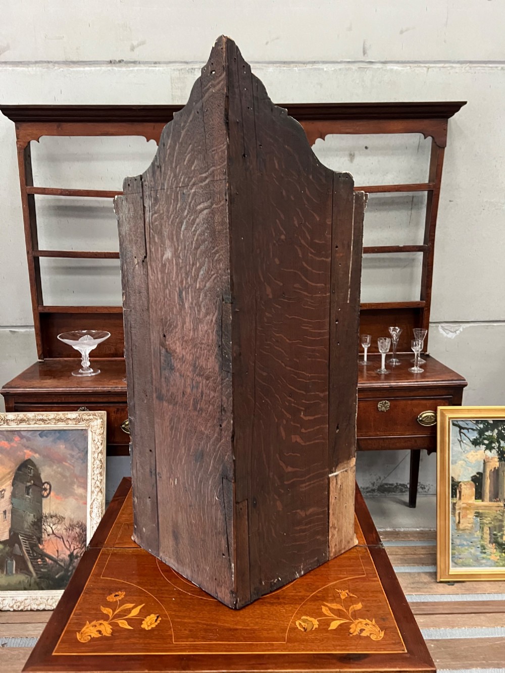 A dark black japanned hanging corner cabinet featuring gilt chinoiserie artwork with birds, architectural pagodas, and brass hinges. View V