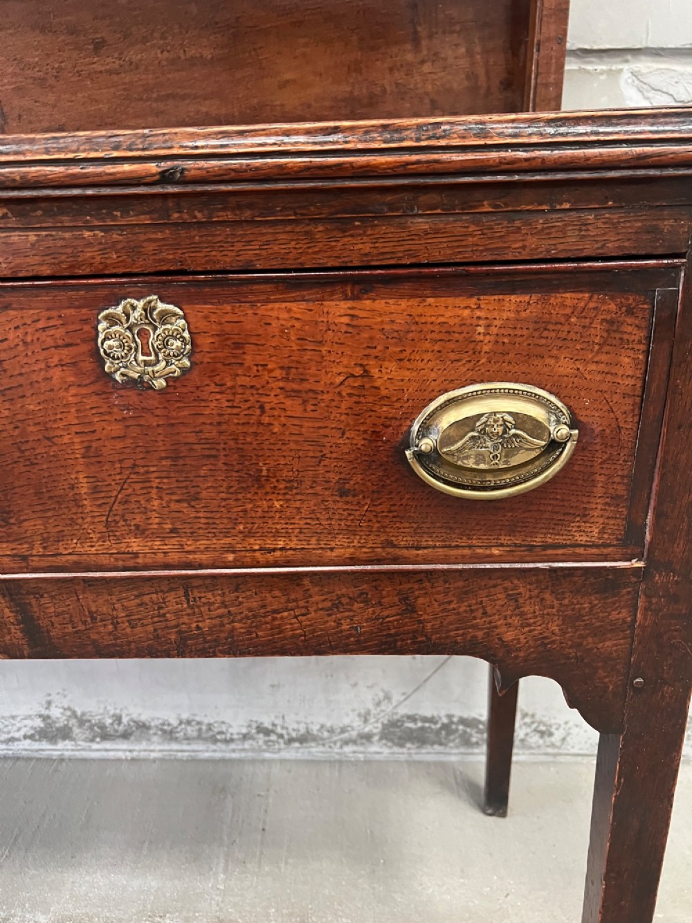 An 18th century oak and elm Welsh dresser featuring an open three-tiered plate rack top above three drawers with brass handles and a shaped apron. View III