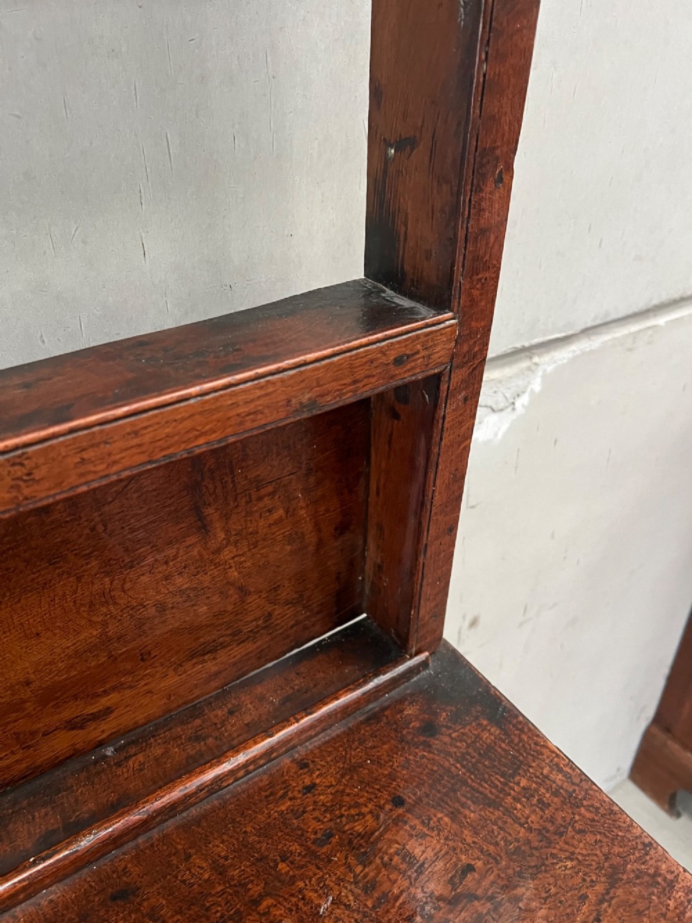 An 18th century oak and elm Welsh dresser featuring an open three-tiered plate rack top above three drawers with brass handles and a shaped apron. View IV