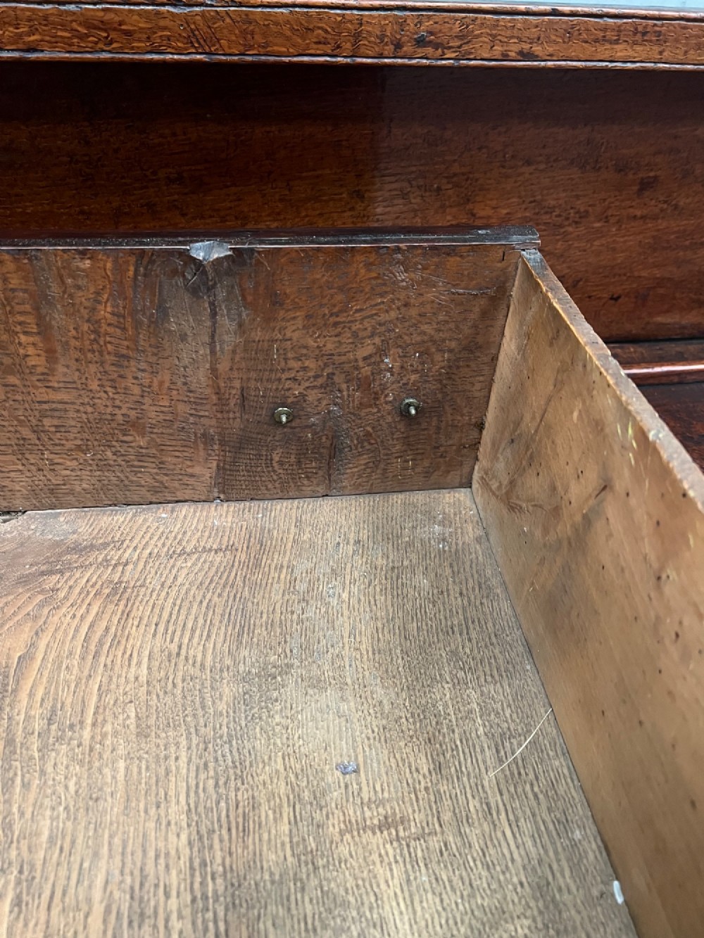 An 18th century oak and elm Welsh dresser featuring an open three-tiered plate rack top above three drawers with brass handles and a shaped apron. View VII