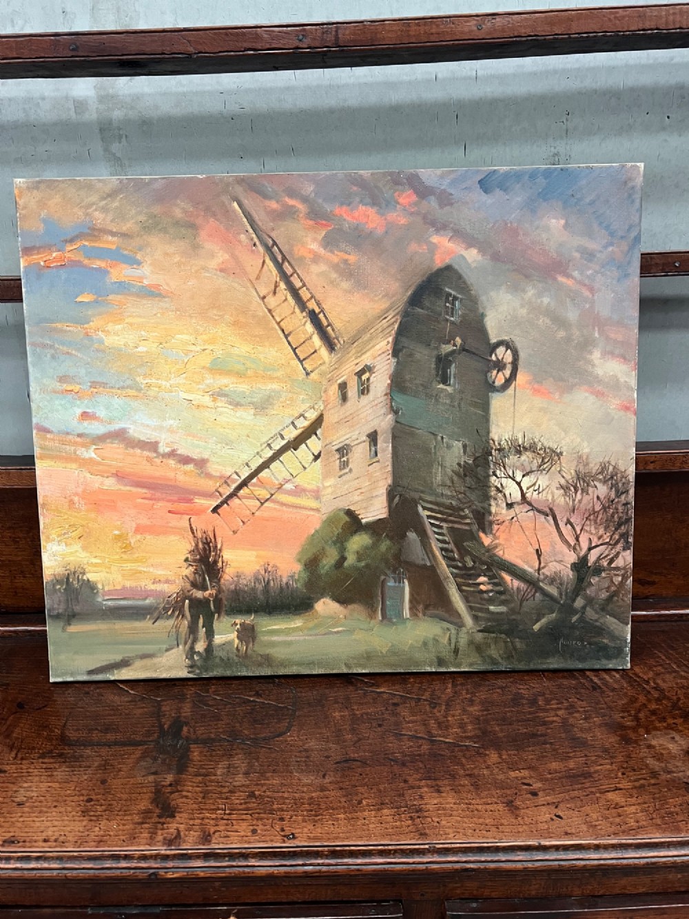 An oil painting depicting a wooden windmill at sunset with a figure walking alongside a dog in a rural landscape.