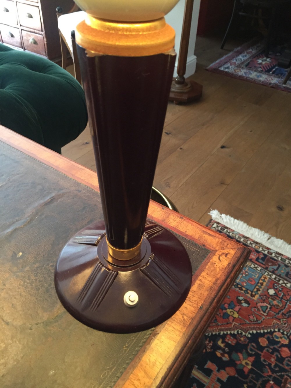 A near pair of Art Deco desk lamps featuring stepped dark brown Bakelite bases, fluted stems, and wide rounded metal shades with internal illuminated glass diffusers. View IV