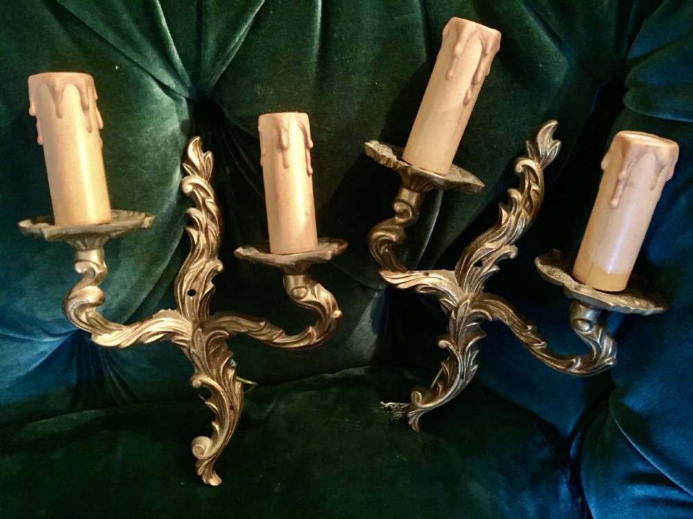 A pair of nineteenth-century French cast bronze two-arm wall sconces decorated with ornate leaf scrollwork and candle-effect sleeves. View V