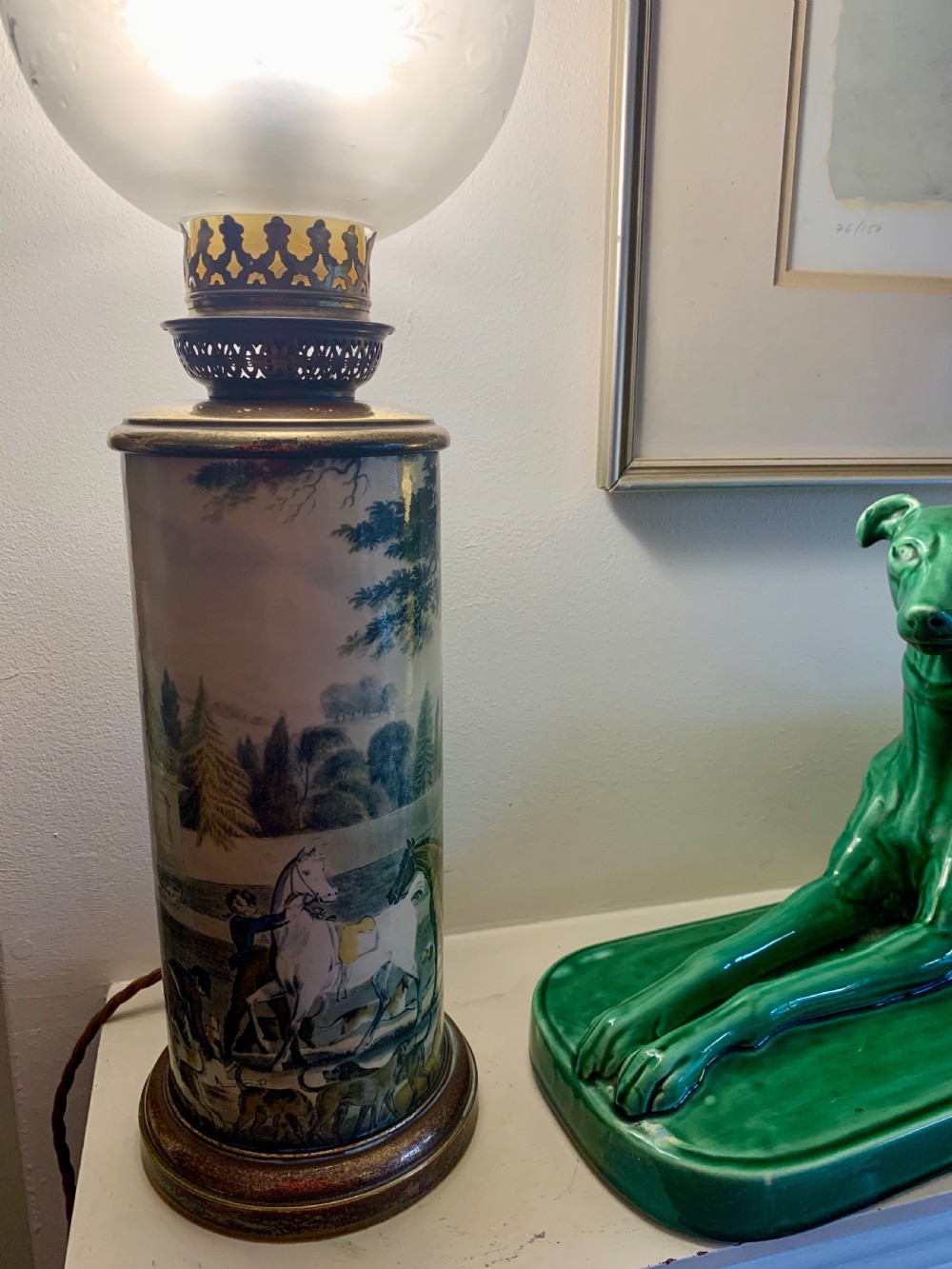 An antique French ceramic cylindrical oil lamp featuring a countryside hunt scene, brass gallery fittings, and a frosted glass globe shade. View III