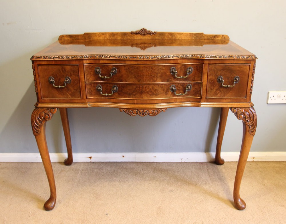 An antique burr walnut server side table featuring carved cabriole legs, brass drop handles, and a carved back gallery.