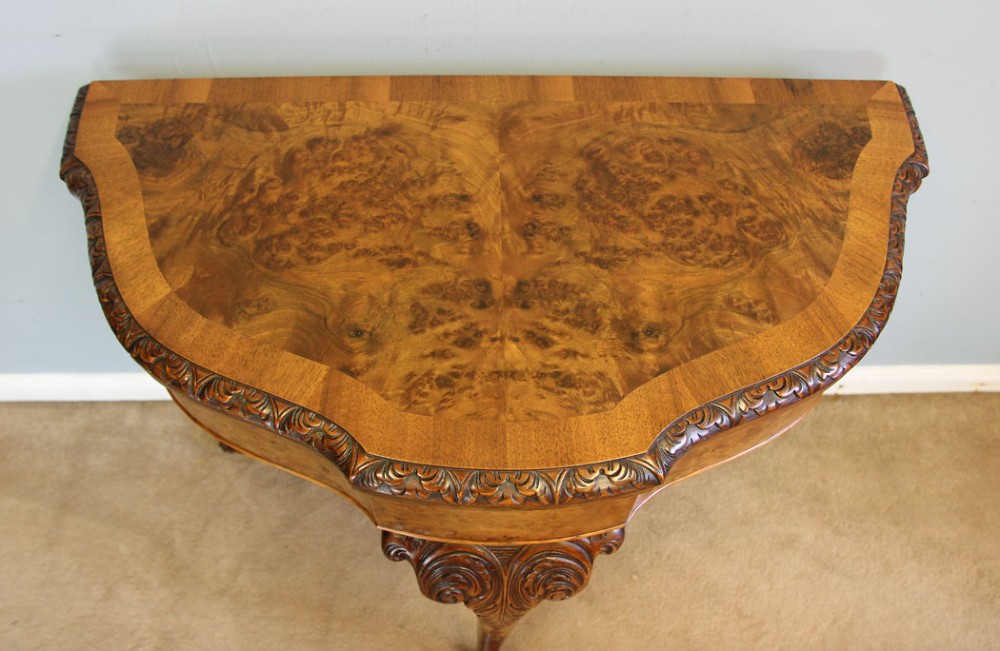 A demi-lune burr walnut fold-over card table featuring carved edges, cabriole legs, and carved ball-and-claw feet. View II