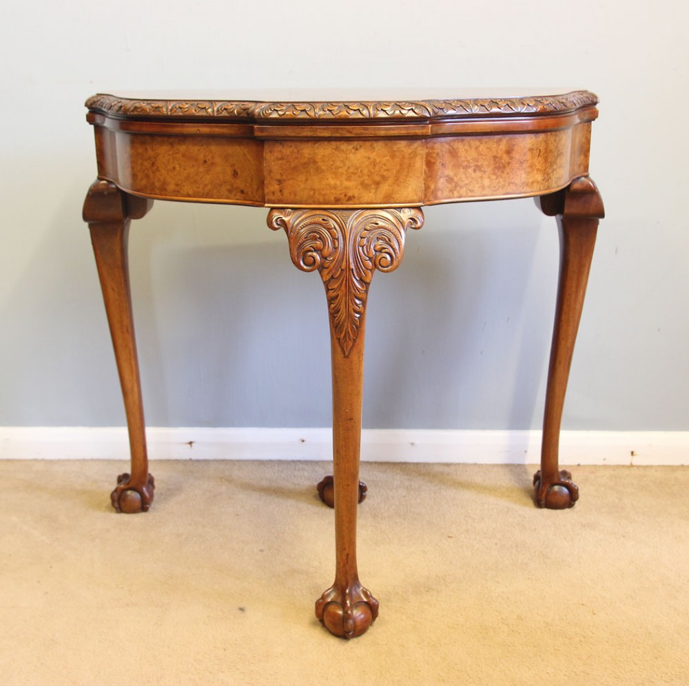 A demi-lune burr walnut fold-over card table featuring carved edges, cabriole legs, and carved ball-and-claw feet. View III