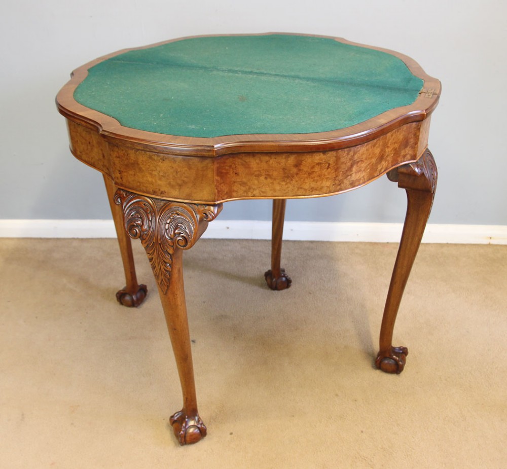A demi-lune burr walnut fold-over card table featuring carved edges, cabriole legs, and carved ball-and-claw feet. View V