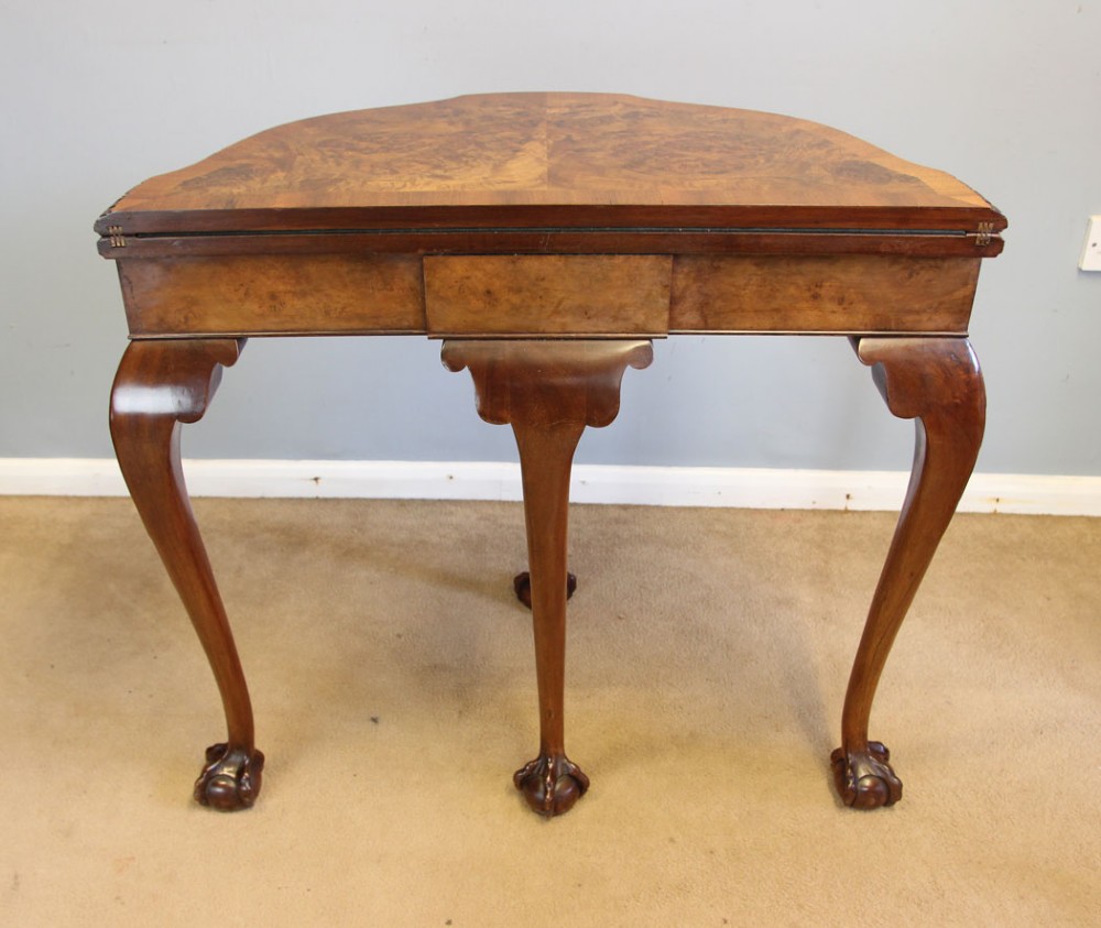 A demi-lune burr walnut fold-over card table featuring carved edges, cabriole legs, and carved ball-and-claw feet. View VI