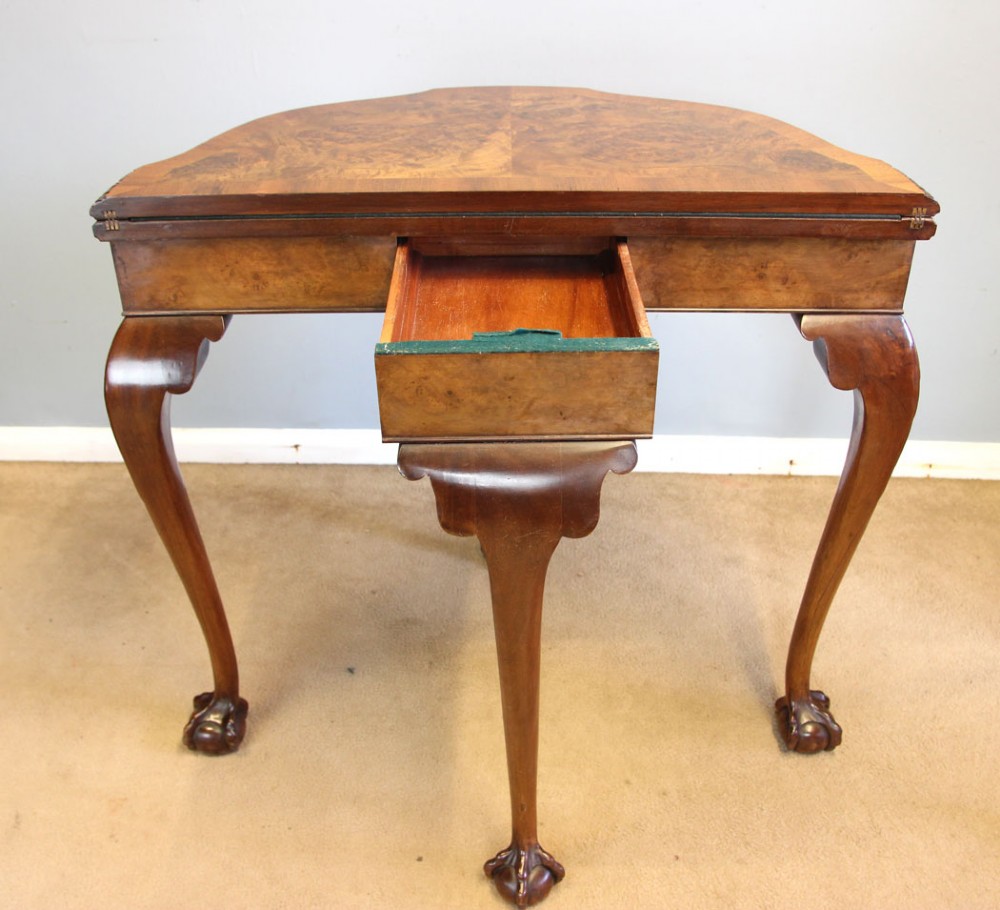 A demi-lune burr walnut fold-over card table featuring carved edges, cabriole legs, and carved ball-and-claw feet. View VII