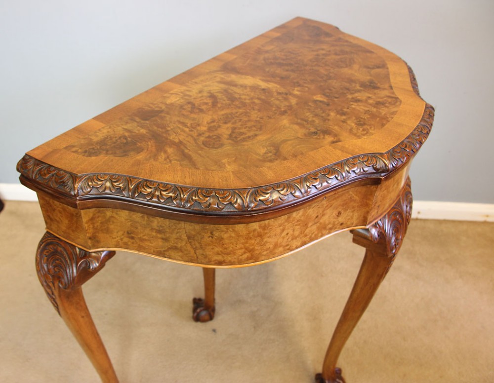A demi-lune burr walnut fold-over card table featuring carved edges, cabriole legs, and carved ball-and-claw feet. View IX