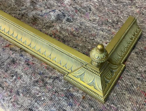 fig 1. An antique Victorian brass fireplace fender featuring a low rectangular kerb with decorative fluted moulding and detailed finials at each end.