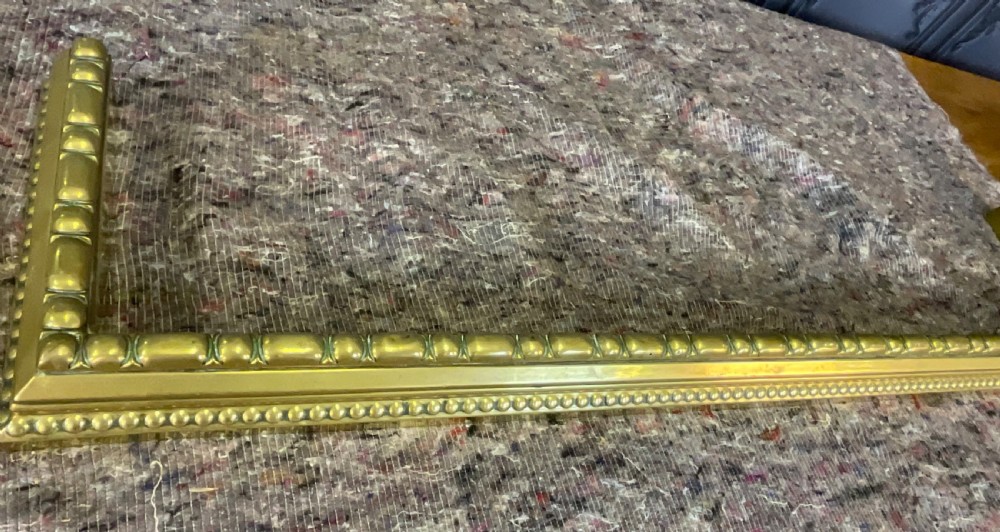 A low rectangular Victorian brass fireplace fender featuring raised beaded moulding and a polished golden finish. View IV