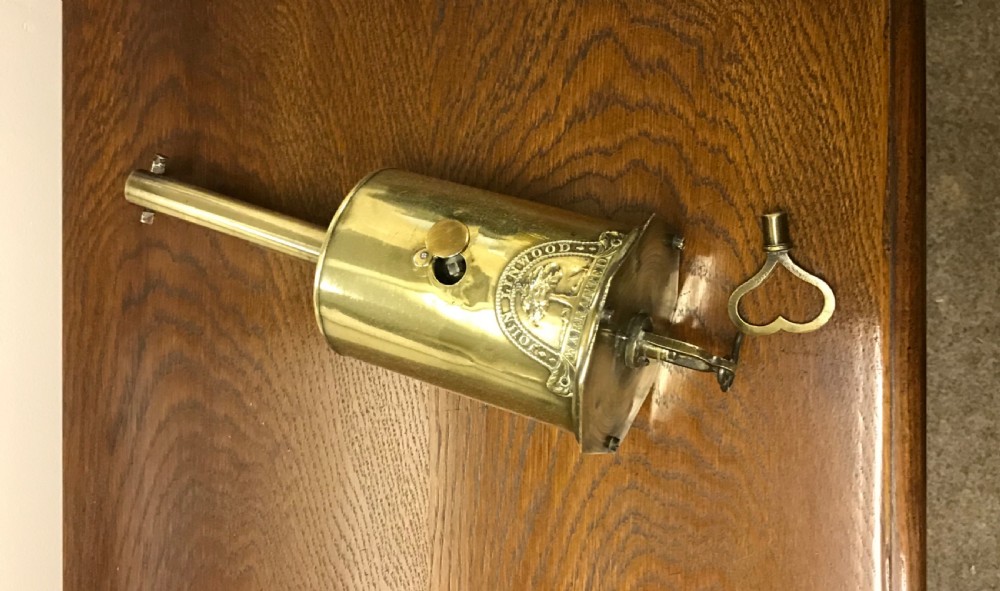 A cylindrical Georgian brass bottle spit jack featuring an embossed maker crest and a long top neck. View II