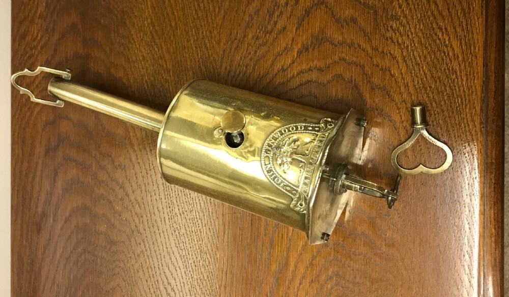 A cylindrical Georgian brass bottle spit jack featuring an embossed maker crest and a long top neck. View V